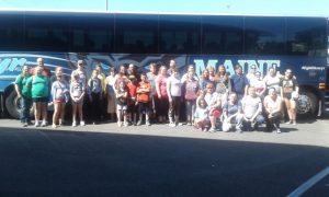 group of 4H youth and adult posing for picture and the bus they are boarding