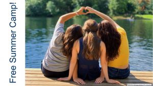 3 female youth sitting back to facing water making a heart with their combined hands