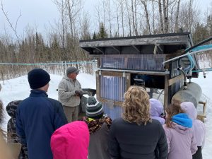 people outside watching maple syrup demonstration