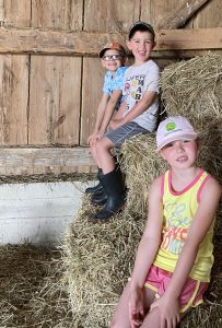 three youth sitting on hay