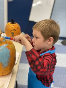 young boy decorating a pumpkin