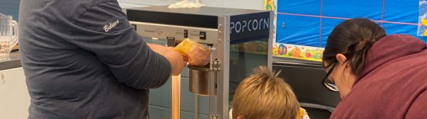 girl making popcorn with young boy and volunteer