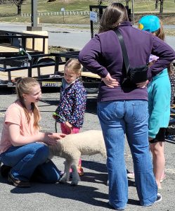 two youth, a baby lamb and adult talking