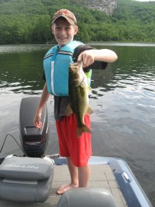 camper in boat holds bass