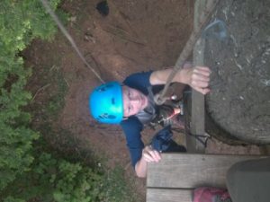 Camper climbing tree ladder to zip line