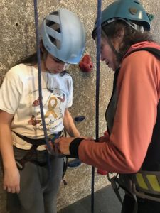 adult volunteer helps youth at climbing wall