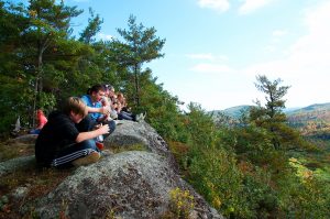 4-H youth campers sitting on a bolder in the forest