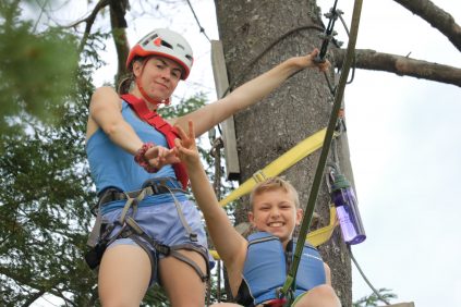 Staff assisting camper at top of zip line tower