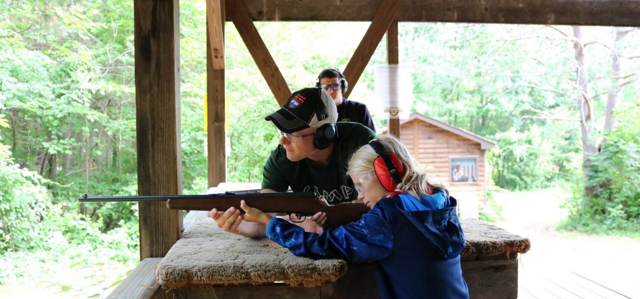 Camper shooting rifle with a warden instructing them