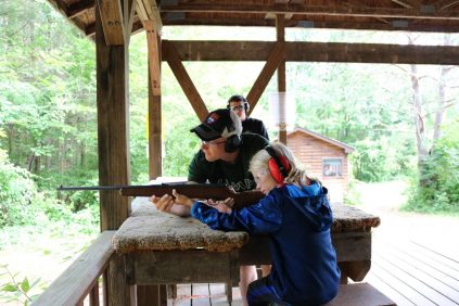 Camper shooting rifle with a warden instructing them
