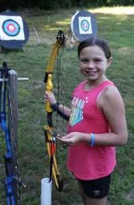 A Camper holding a bow at the archery range