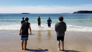 group of participants on a beach wading into the ocean