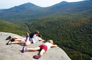 participants laying on a huge rock outcropping overlooking a Maine mountain range in autumn