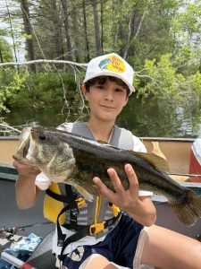 camper holding up a bass, sitting in a canoe