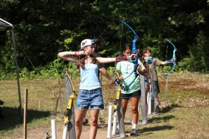 three campers on the archery range preparing to shoot arrows