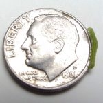 A False Armyworm larva crawling on the rim of a U.S. dime