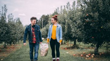 Young couple with a bushel of apples in an apple orchard