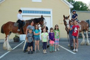 smiling kids with two horses and two riders
