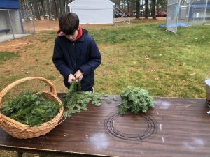a boy making a holiday wreath with branches