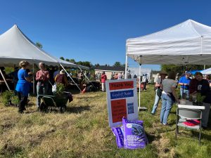 Several people shopping for plants at a sale, with donated Coast of Maine soil in the foreground.