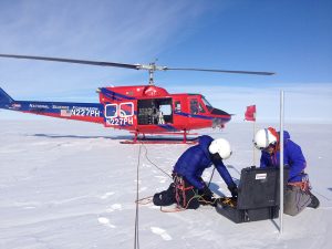 Lynn Kaluzienski and Peter set up equipment on the ice sheet near their helicopter