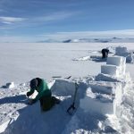 Researchers cut blocks of snow to build a snow wall as a wind break