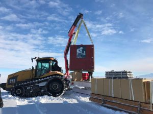 South Pole Traverse Team helps unload gear at our new camp site. A portrait of the Norwegian explorer Roald Amundsen adorns the cargo box that houses the robots.