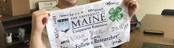 Tyler holds up 4-H flag signed by participating school children