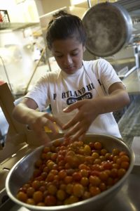girl washing cherry tomatoes