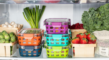 Storage containers in a refrigerator with fresh produce on the shelves