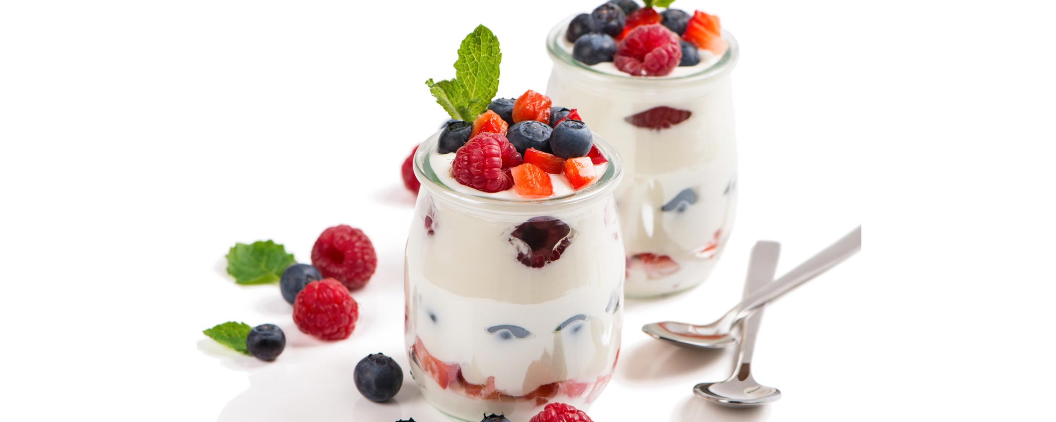 Two yogurt fruit parfaits with raspberries and blueberries in clear jars