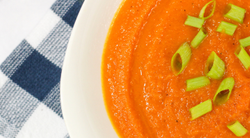 curried carrot soup with chive toppings in a white bowl