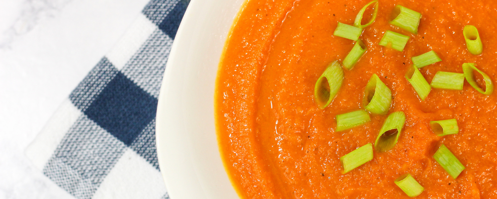 curried carrot soup with chive toppings in a white bowl