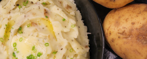Potatoes next to mashed potatoes in a bowl.