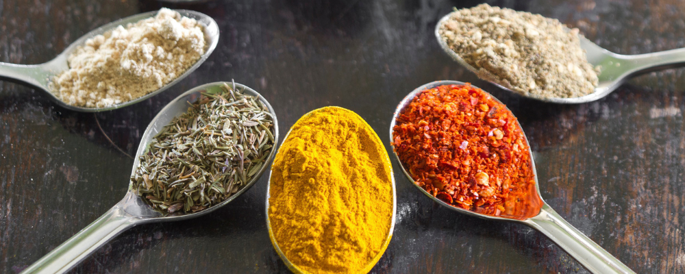 Five spoonfuls of different spices with a variety of colors.