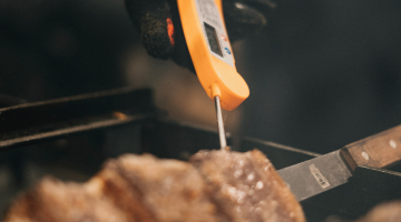 A food thermometer taking the internal temperature of steak.