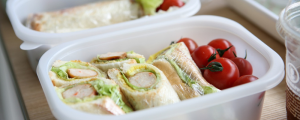 Lunch container with tomatoes and sandwich wraps.