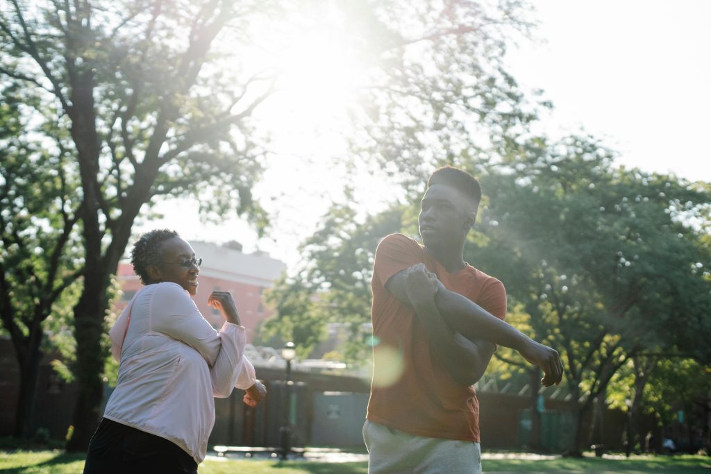 Mother and son stretching at a park together.