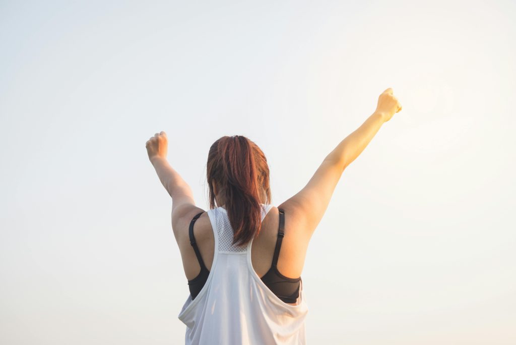 A woman stretching both arms in the air.