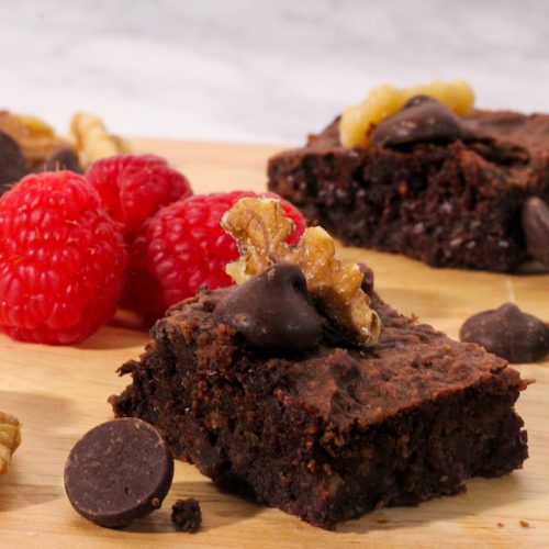 two-bite black bean brownies with walnuts and raspberries on a cutting board