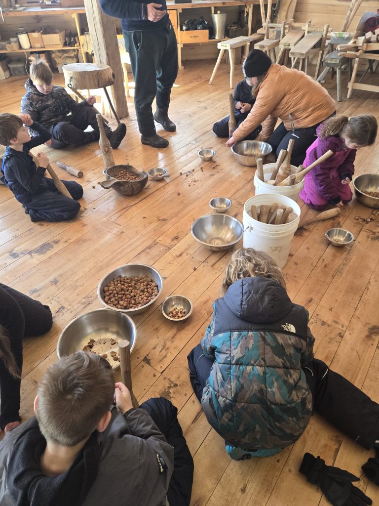 4-H Youth and volunteer smashing acorns. Making acorn flour