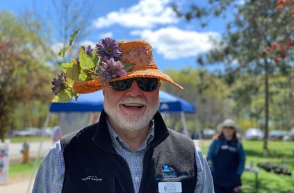 image of smiling man wearing a hat with flowers on the brim