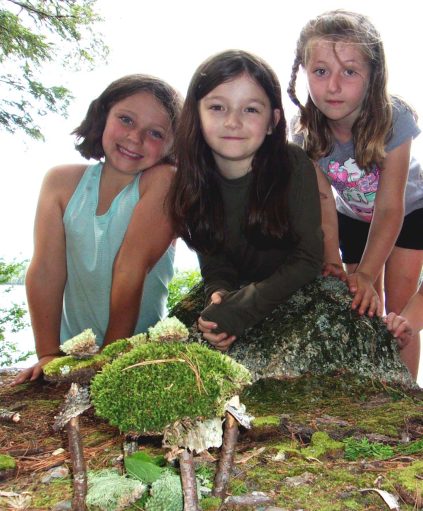 Image of 3 camp participants in front of a fairy house creation