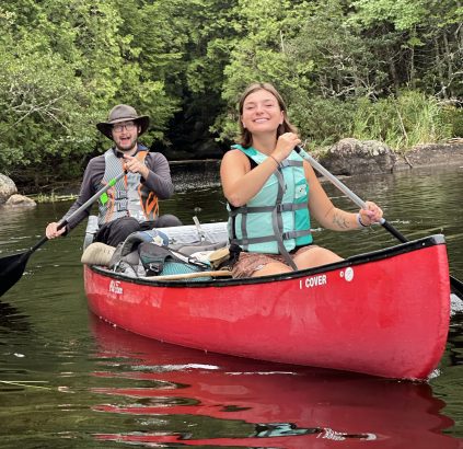 Staff member and camper paddling in a canoe