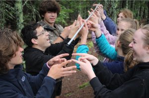 Group of young teens holding a long rod as part of a team building excersize