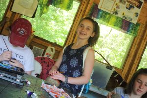 Three campers sitting at a table working on art projects