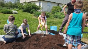 Kids working together to mix compost and dirt to plant their tomatoes.