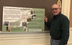 Master Gardener Volunteer, Dan DeLong, displays a sign titled, "Preserving Biodiversity in the Urban Landscape"