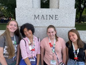 Four 4-H youths sitting in front of a Maine statue