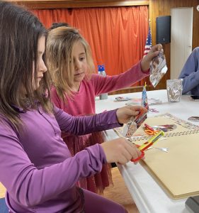 Two young girls cutting and gluing pictures into a scrapbook